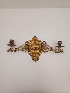 an ornately designed wall light with three candles on it's side and one candle holder in the middle