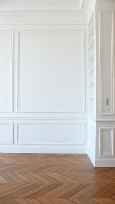 an empty room with white walls and wood flooring in the center, along with wooden parquet floors