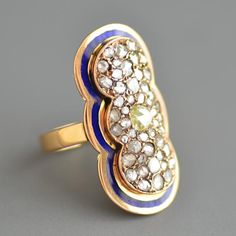 A stunning antique Georgian Era (1714-1837) rose cut diamond and blue enamel plaque ring in 18k yellow (ever so slightly rosy) gold. This beautiful and impressive ring features a central larger pale yellow rose cut diamond surrounded by a pave of various sized whiter rose cut diamonds that all glitter and shine like crazy bead set in a shapely bezel setting that sits atop a gold plate that curves to hug the finger and has an elegant ribbon of cobalt blue enamel to echo the shape of the top diamo Yellow Gold Enamel Jewelry With Rose Cut Diamonds, Fine Jewelry Yellow Gold Enamel Ring With Diamond Accents, Fine Jewelry Yellow Gold Diamond Ring With Enamel, Yellow Gold Enamel Ring With Diamond Accents, Yellow Gold Enamel Ring With Single Cut Diamonds, Art Deco Blue Diamond Ring With Rose Cut, Art Deco Blue Rings With Rose Cut Diamonds, Blue Art Deco Diamond Ring With Rose Cut, Art Deco Blue Rose Cut Diamond Rings