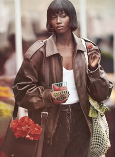 a woman is walking down the street with some fruit in her hand