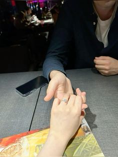 two people sitting at a table with their hands touching each other's fingertipss