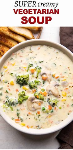 a bowl of soup with broccoli, mushrooms and carrots in it next to bread