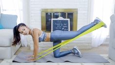 a woman is doing exercises on her yoga mat in the living room while holding a resistance band