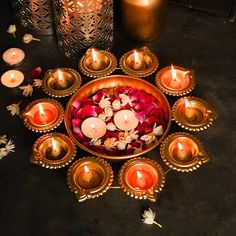 there are many candles and flowers in the bowl on the table next to each other