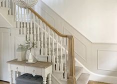 a white staircase with a table and vase on it