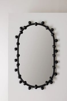 a mirror that is on the wall with some black balls in front of it and a white wall behind it