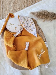 a stuffed animal is wrapped in a blanket on a white surface with an orange pillow