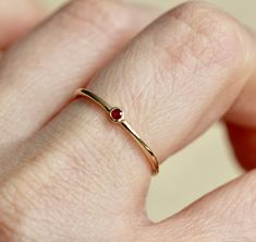 Perfect as a stacker or standing on its own, our Ruby ring is just the cutest! - Bezel set natural Ruby measures 2mm across. - Round band measures 1.2mm - Available in 14K yellow, rose or white gold Looks great as a stacking ring, or a midi ring. Processing times - Current processing time is 2 - 4 weeks. Each Item is handmade to order with love and care! In Stock Items - Contact Liesel Love with any rush order questions, or to see if we have anything ready made and in stock. Returns - Liesel Lov Small Red Jewelry Perfect For Gifting, Red Stackable Ruby Ring For Anniversary, Stackable Red Ruby Ring, Adjustable Red Birthstone Promise Ring, Everyday Red Gemstone Ring, Red Ruby Stackable Rings For Anniversary, Red Birthstone Ring With Round Band, Red Round Ring For Everyday, Anniversary Ruby Red Stackable Rings