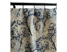 a blue and white paisley print curtain hanging from a black metal rod with an iron bar