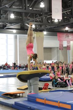 a woman in pink shorts doing a trick on a trampoline while people watch