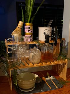 a wooden shelf filled with lots of bottles and glasses next to a potted plant