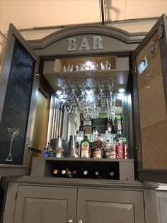 a bar with lots of bottles and glasses on it's counter top, next to a chalkboard