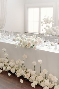 the table is set with white flowers and place settings for guests to sit down at