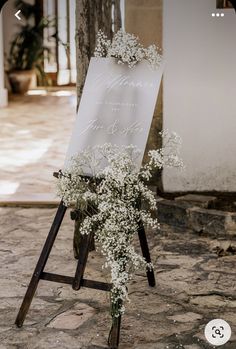 an easel with flowers on it and a sign that says welcome to the bride