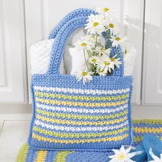 a crocheted bag with flowers in it sitting next to a white door handle