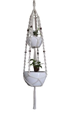 a white hanging planter with two plants in it and beads around the bottom part