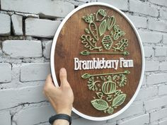 a hand is holding up a sign that says brandyberry farm on the side of a brick wall