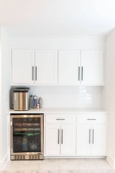 a kitchen with white cupboards and stainless steel appliances on the counter top in front of an oven