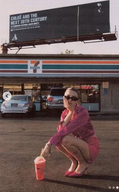 a woman kneeling down in front of a gas station holding a bucket and talking on the phone