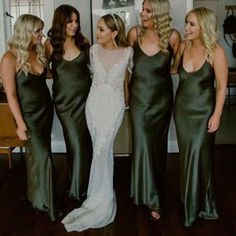 four beautiful women standing next to each other in long dresses and one is wearing a wedding dress