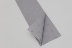 a piece of gray paper with white polka dots on it, folded up to look like a tie