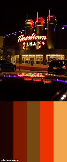 an image of a building that is lit up at night with lights on it and cars parked in front