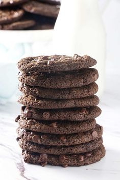 a stack of chocolate cookies sitting on top of a counter next to a glass of milk