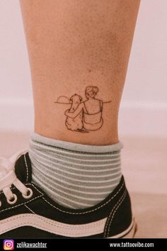 a small tattoo on the ankle of a woman's foot with an image of two people