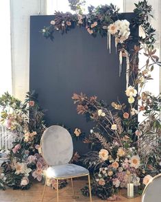 a chair sitting on top of a wooden floor next to a wall covered in flowers