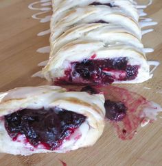 croissants with blueberries and cream cheese are on a cutting board, ready to be eaten