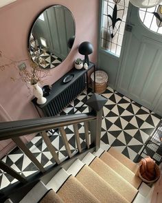 the stairs are decorated with black and white geometric tiles, along with a round mirror on the wall