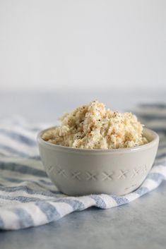 a white bowl filled with food sitting on top of a blue and white striped towel