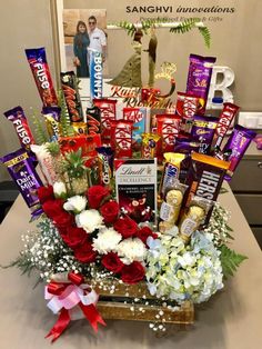 a basket filled with assorted chocolates and flowers sitting on top of a table