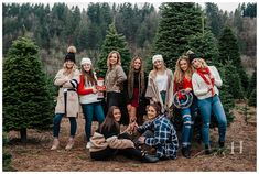 a group of young women standing next to each other in front of christmas tree trees