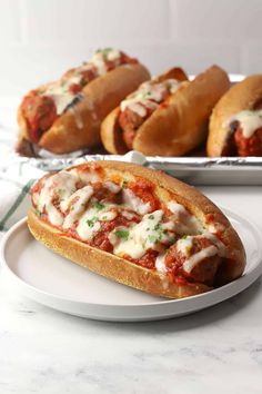 two hot dogs on buns covered in sauce and parmesan cheese are sitting on a plate