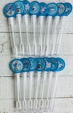 six toothbrushes are lined up on a white wooden table with snowman faces