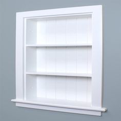 a white book shelf with three shelves on the top and bottom, against a gray wall