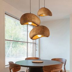 a dining room table with four chairs and three lights hanging from it's ceiling