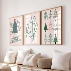 three christmas trees are hanging on the wall above a bench with pillows and throw pillows