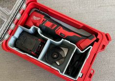 a red tool box filled with tools sitting on top of a gray floor next to a window