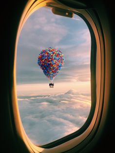 an airplane window with a bunch of balloons in the sky