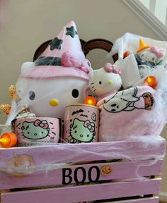 a hello kitty themed gift basket in a pink crate with candles and stuffed animals on it