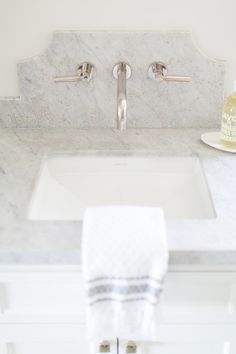 a white bathroom sink sitting under a faucet next to a towel on top of a counter