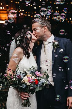 a bride and groom kissing in front of bubbles