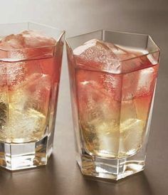 two glasses filled with ice sitting on top of a table