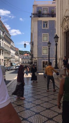 people are walking down the street in front of buildings