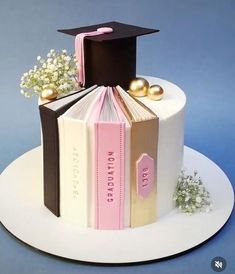 a graduation cake with a book and flowers on top