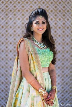 a woman in a green and yellow lehenga with gold jewelry on her neck