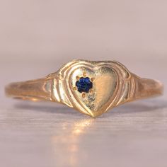 The Vancouver: Yellow Gold Heart Ring With Natural Blue Sapphire. This Charming Ring Features A Layered Heart Center, Showcasing A Single Round Brilliant Cut Natural Sapphire Slightly Off-Center. Crafted With Care In Yellow Gold, This Ring Offers A Timeless And Understated Design. Currently Sized At 4, It Provides The Option For Adjustment To Any Finger Size Upon Request, Although An Additional Charge May Apply. Blue Sapphire Heart Ring, Heirloom Blue Sapphire Promise Ring, Heart-shaped Blue Birthstone Ring Gift, Blue Gemstone Heart Ring For Wedding, Blue Heart Cut Birthstone Ring For Gift, Blue Heart Cut Birthstone Ring As Gift, Heirloom Blue Birthstone Ring For Promise, Heirloom Blue Birthstone Promise Ring, Blue Heart Ring For Wedding Fine Jewelry