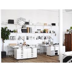 an office with white desks and shelves on the wall